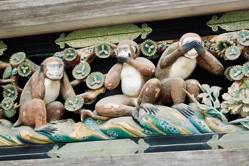 Three carved wooden monkeys representing hear no evil, speak no evil, and see no evil.